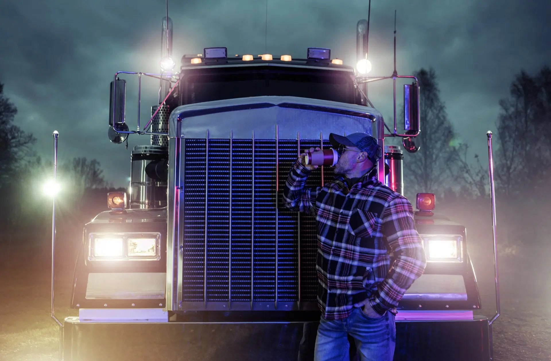 truck driver drinking coffee in front of truck